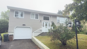 A two-story house with a garage, a front porch, and a well-maintained lawn.