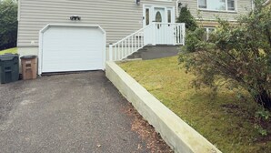 A two-story house with a garage, a front porch, and a well-maintained lawn. - Zen Cove- Home in West Saint John. 7 minutes from the Irving Nature Park. (Saint John)