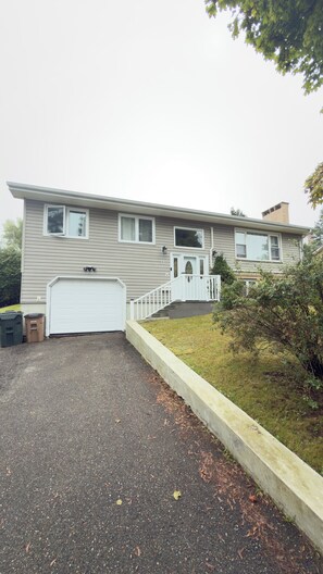 A two-story house with a garage, a front porch, and a well-maintained lawn. - Zen Cove- Home in West Saint John. 7 minutes from the Irving Nature Park. (Saint John)
