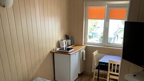 A compact kitchenette with a small fridge, a kettle, and a window with orange blinds. - Room for 2 People With Kitchenette (Mielno)