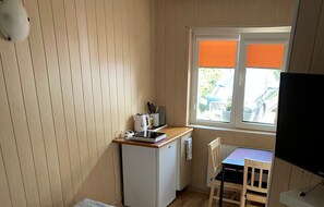 A compact kitchenette with a small fridge, a kettle, and a window with orange blinds. - Room for 2 People With Kitchenette (Mielno)