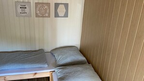 A small, single-bed room with a wooden headboard and a wall-mounted bed. There are three framed motivational quotes on the wall. - Room for 2 People With Kitchenette (Mielno)