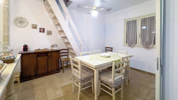 Un comedor con una mesa y sillas de madera, una escalera y un reloj en la pared.