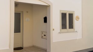 Un bâtiment blanc avec une porte, une fenêtre avec des volets et une petite boîte aux lettres.