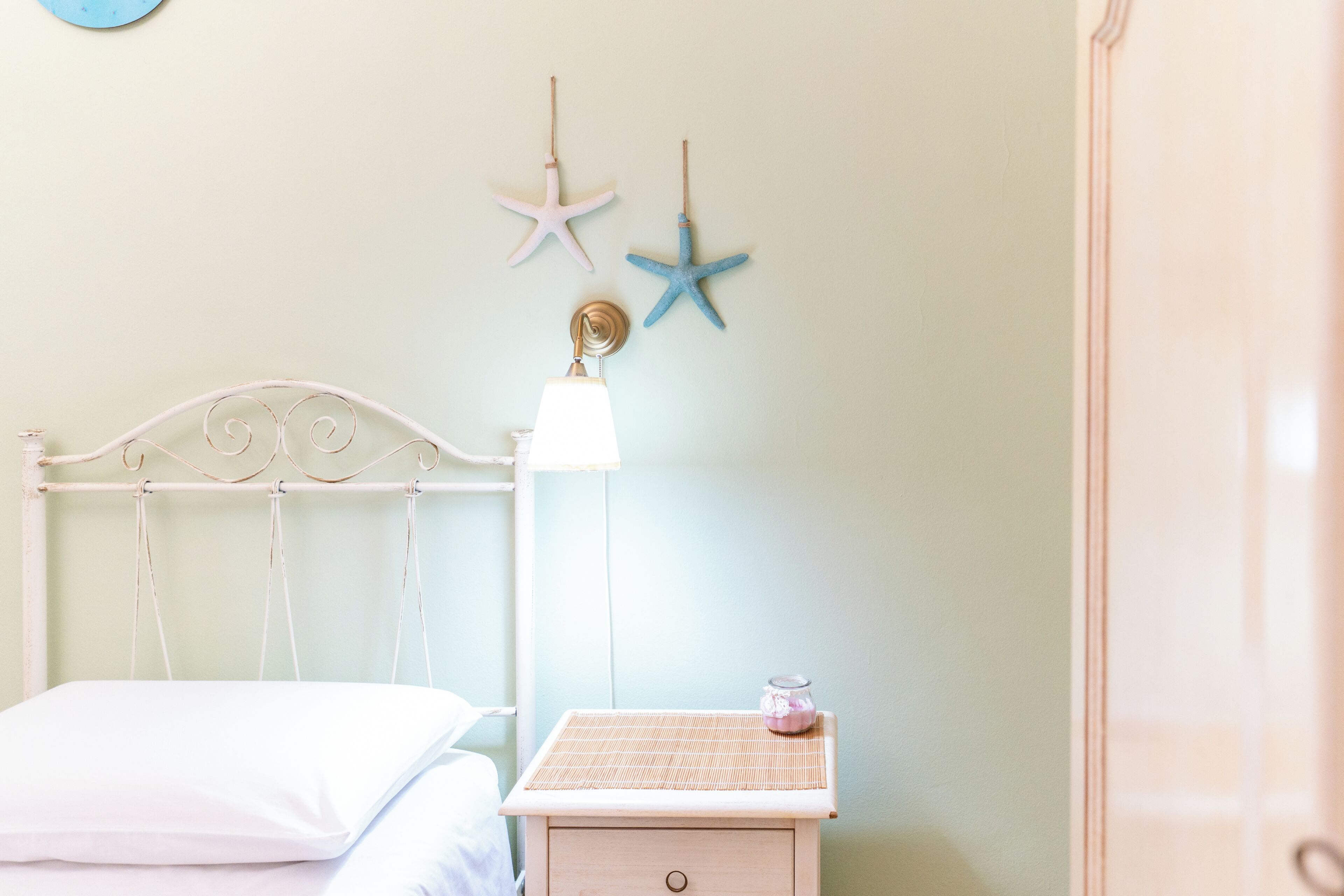 Un dormitorio con una cama, una mesita de noche con lámpara y dos adornos de estrella de mar en la pared.