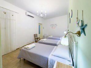 Een hotelkamer met twee bedden, een stoel, een bureau, een kroonluchter en een muur met decoratieve objecten.