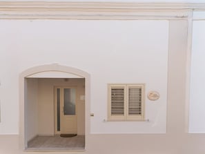 A building entrance with a door, a small window with shutters, and a doorbell. - B&B Palmarì (Sannicola)