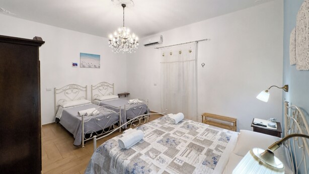 Une chambre avec deux lits, un lustre, une table de chevet, une lampe et une fenêtre avec des rideaux.