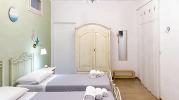 Une chambre d’hôtel avec deux lits, un lustre, une armoire et un miroir.
