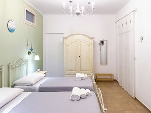 A hotel room with two beds, a chandelier, a wardrobe, and a mirror. - B&B Palmarì (Sannicola)