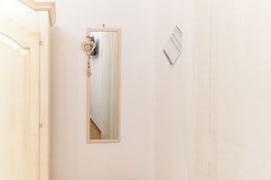 A room with a mirror on the wall, a door, and a wall-mounted light switch. - B&B Palmarì (Sannicola)