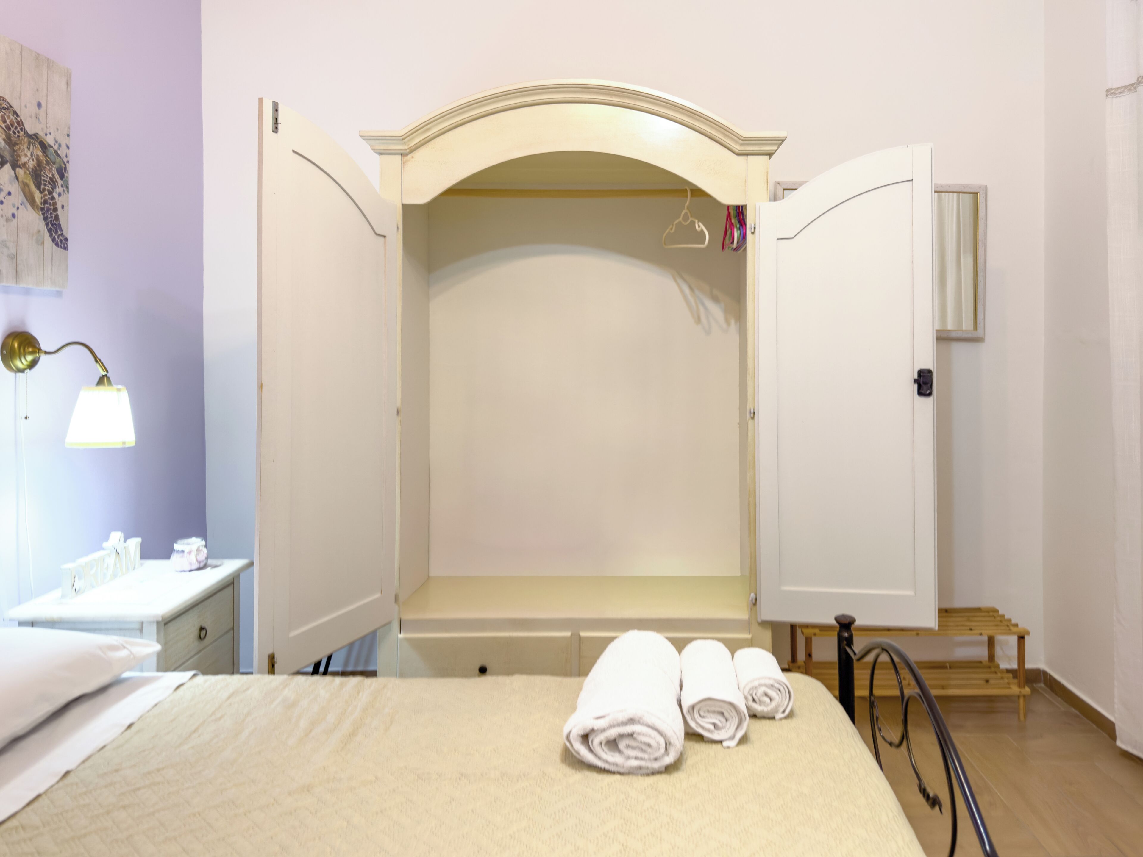 Une chambre à coucher comprenant un lit, une table de chevet, une lampe et une armoire avec un miroir.