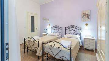 Habitación de hotel con dos camas, una mesita de noche, un aparador y una puerta.