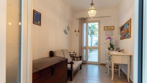 Un couloir avec une commode en bois, un canapé, un bureau orné d’un vase de fleurs et un lustre.
