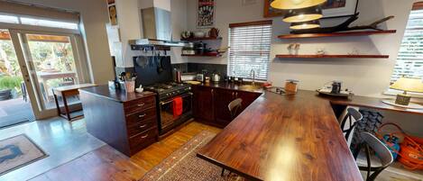 A modern kitchen with a central island, wooden cabinets, and a large dining table.