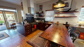 A modern kitchen with a central island, wooden cabinets, and a large dining table.