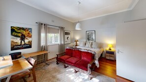 A bedroom with a bed, bedside table, lamp, and a poster on the wall.