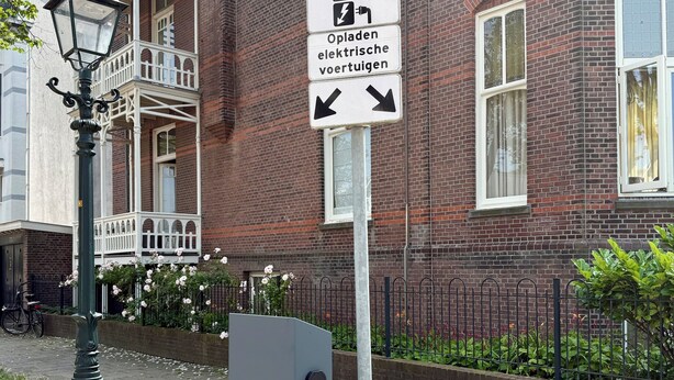 En parkeringsskylt med en bil-symbol och en symbol för laddstation för elfordon, som pekar åt höger.