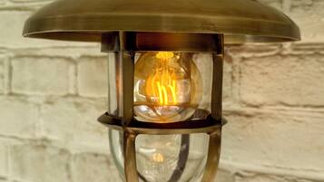 Une lanterne murale dotée d’un boîtier en verre transparent et d’une flamme visible.