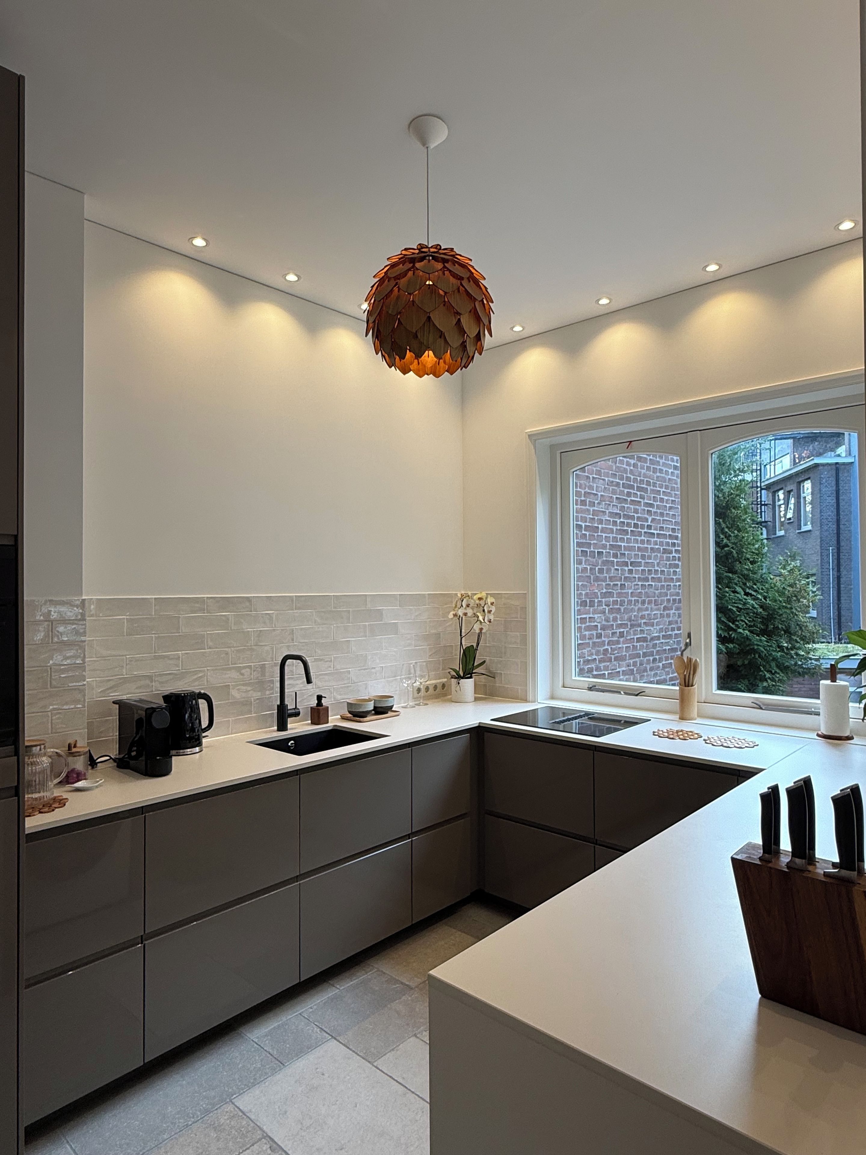 A modern kitchen with a central island, a built-in sink, and a pendant light.