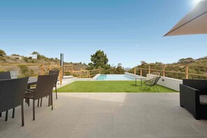 A rooftop terrace with a swimming pool, outdoor furniture, and a view of the surrounding landscape.