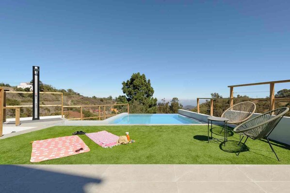 Un jardin avec une piscine, une pelouse et du mobilier d’extérieur.