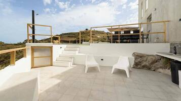 Una terraza en la azotea con zona de estar, una escalera y vistas del paisaje circundante.