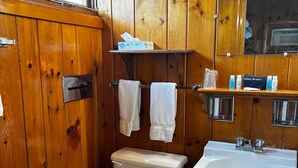 A wooden-paneled bathroom with a toilet, sink, and a mirror above the sink. - Cozy 1BR hotel room, Hamilton - #343 Hiawatha (Hamilton)