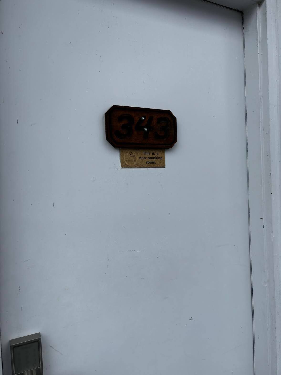 Porta com placa de proibido fumar e número do quarto.