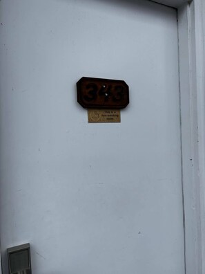 Una puerta con un cartel de no fumar y una placa con el número de habitación.