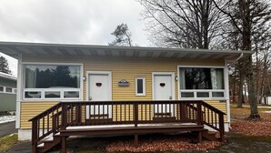 A small, single-story building with a wooden deck and a bench in front. - Cozy 1BR hotel room, Hamilton - #343 Hiawatha (Hamilton)