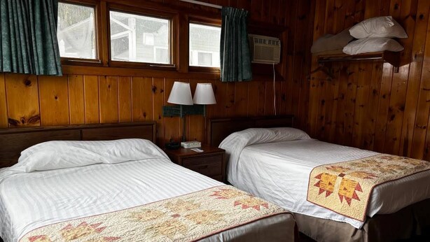 A room with two beds, a nightstand with lamps, and a window with curtains. - Cozy 1BR hotel room, Hamilton - #343 Hiawatha (Hamilton)