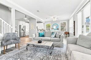 A modern living room with a grey sofa, patterned armchair, and a coffee table. - Poolside Paradise - Access To Pool, Walk To Beach! (Rosemary Beach)