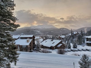 Une ville de montagne enneigée, avec des bâtiments et des voitures garées.