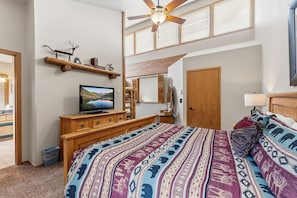 A bedroom with a bed, a television, a wooden dresser, a ceiling fan, and a window with blinds. - Two Bedroom, Two Bath with Easy Ski Access and Mountain Views (Breckenridge)