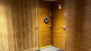 A room with wooden panel walls, a door with a number plate, and a doormat. - Meribel Mottaret Apartment at the Foot of the Slopes, Sleeps 5, All-Inclusive (Les Allues)