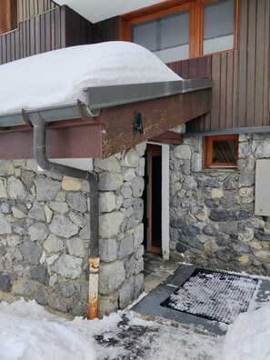 Ein Steinhaus mit schneebedecktem Dach und einer Metallrinne.