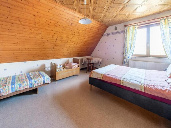 A bedroom with two beds, a small table, and a window with curtains.