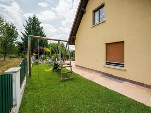A residential property with a well-maintained lawn, a swing set, and a house with a window and a door.
