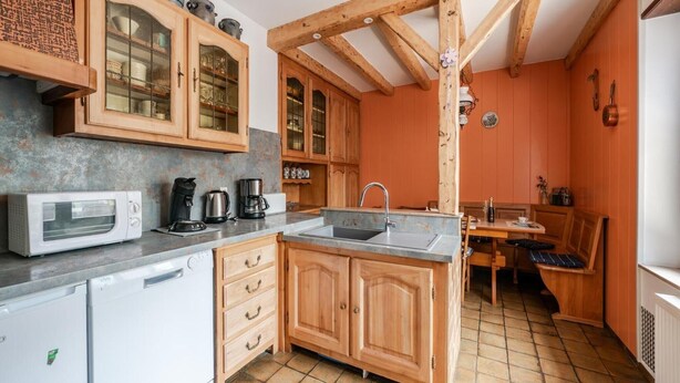 Una cocina compacta con armarios de madera, lavavajillas integrado y un comedor con banco.