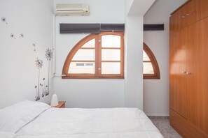 A bedroom with a bed, a wardrobe, and two windows with arched tops. - 3-Bedroom Urban Apartment - Central & Comfortable (Las Palmas de Gran Canaria)