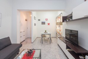 A modern living room with a sofa, a coffee table, a TV, and a dining area with a table and chairs. - 3-Bedroom Urban Apartment - Central & Comfortable (Las Palmas de Gran Canaria)