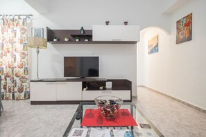A modern living room with a flat-screen TV, a glass coffee table with decorative items, and a red placemat. - 3-Bedroom Urban Apartment - Central & Comfortable (Las Palmas de Gran Canaria)