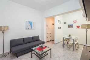 A modern living room with a sofa, coffee table, and a dining area with chairs and a table. - 3-Bedroom Urban Apartment - Central & Comfortable (Las Palmas de Gran Canaria)