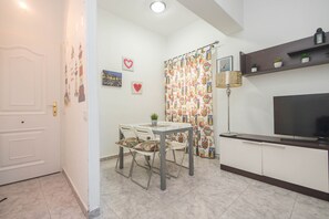 A compact living space with a dining area, a television, and a small kitchen. - 3-Bedroom Urban Apartment - Central & Comfortable (Las Palmas de Gran Canaria)