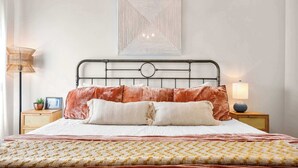 Ein ordentlich gemachtes Bett mit einem gemusterten Überwurf, zwei Kissen und einem Kopfteil mit einem kreisförmigen Design.