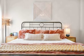 Uma cama bem arrumada com colcha estampada, duas almofadas e cabeceira com design circular.