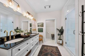 A modern bathroom with dual sinks, a large mirror, and a walk-in shower. - Apple Street Getaway - Fire Pit & Close to Main St (Fredericksburg)