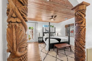 A bedroom with a large bed, wooden ceiling, and carved wooden columns. - The Rustic Door - Hot Tub & 1 Block from Main St (Fredericksburg)
