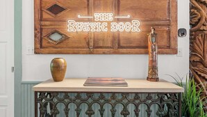Decoración rústica de pared con el texto 'THE RUSTIC BOOK' y un jarrón decorativo sobre una mesa.